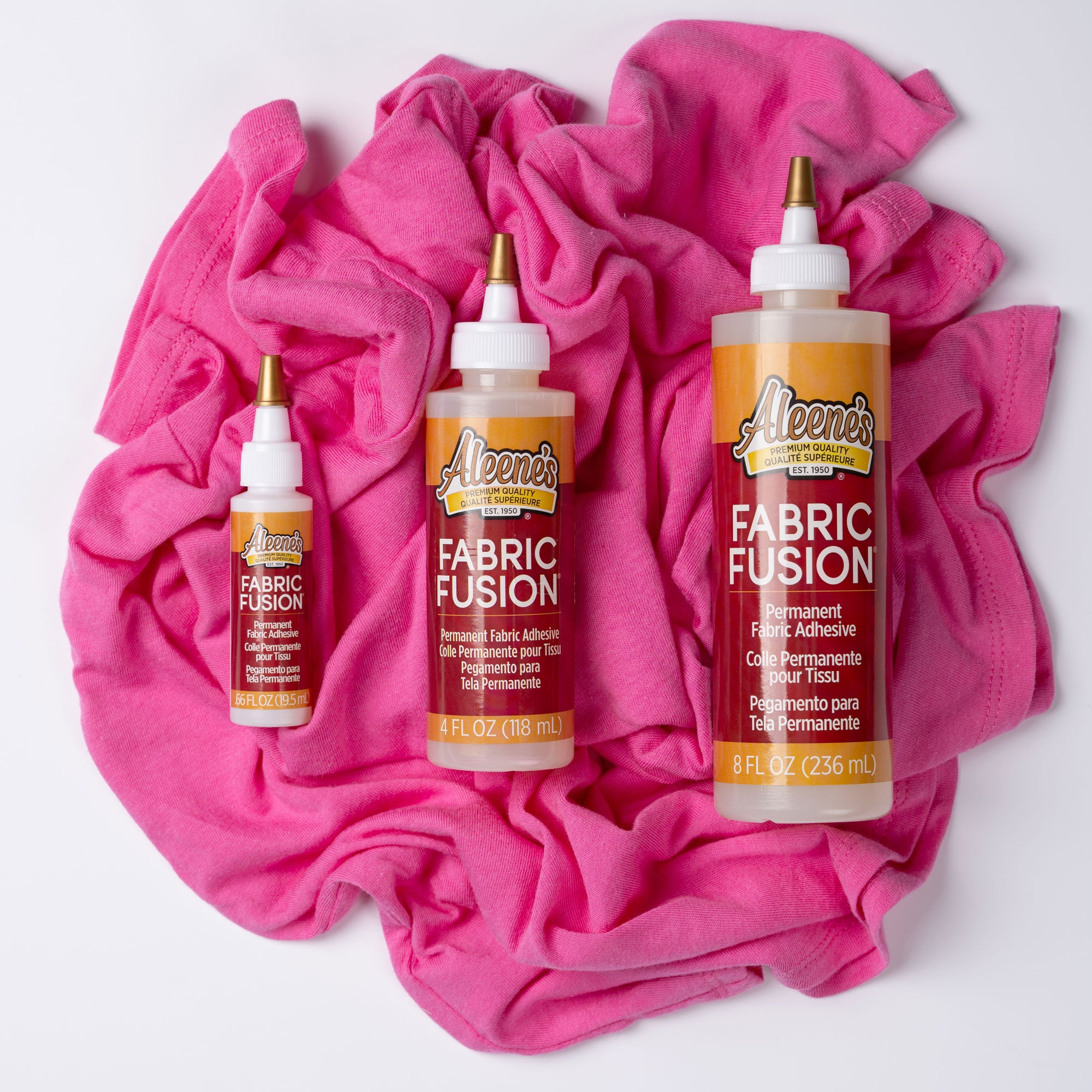 Aleene's fabric fusion glue in 3 sizes on a pink fabric 